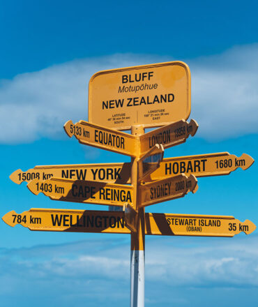 yellow directional sign against a backdrop of a blue sky in new zealand.